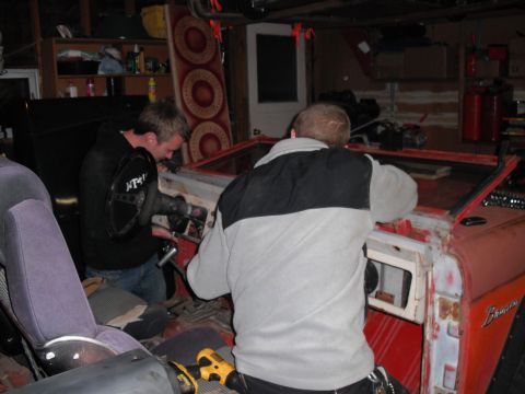 1968 Ford Bronco - Men are working on the interior of a red 1968 Ford Bronco, possibly during a restoration or repair.