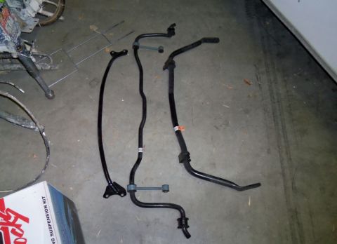 2000 Mercury Grand Marquis - Various suspension components, including four sway bars and a suspension kit box, are laid out on a concrete floor.