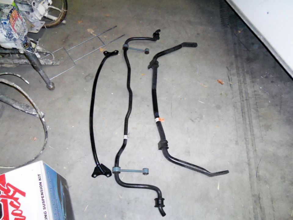 Several black metal suspension bars and a box labeled 'Rocky Mountain Suspension Kit' on a concrete floor