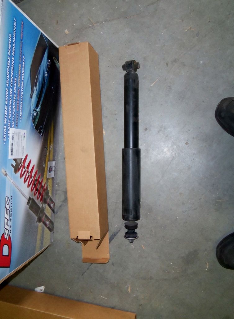 Black shock absorber next to a cardboard box with red springs visible inside