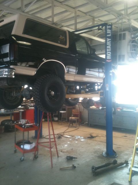 1993 Ford Bronco - This Ford Bronco is up on a lift in a garage, likely undergoing maintenance or repair.