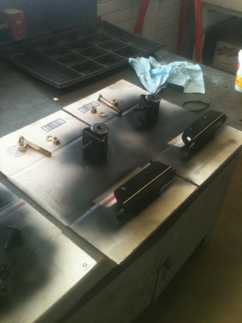 1993 Ford Bronco - Automotive parts are laid out on a workbench, covered in spray paint overspray, ready for further work.