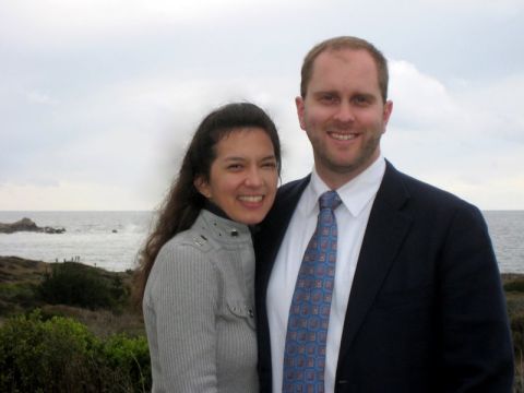 1996 Ford Bronco - A couple smiles for a photo taken outdoors with the ocean in the background. A watermark is visible in the lower right corner.