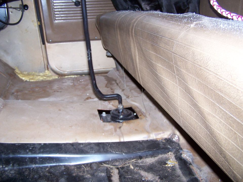 Interior shot of a vehicle's floor and bench seat, showing a floor shifter mechanism