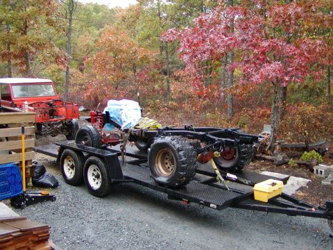 1976 Ford Bronco - A red 1976 Ford Bronco body is parked next to a trailer carrying a chassis.
