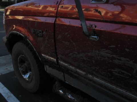 1995 Ford F-150 - A muddy 1995 Ford F-150 is seen from the side, covered in dirt after offroading.