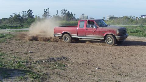 1995 Ford F-150 - This red 1995 Ford F-150 is captured mid-drift, sending a cloud of dirt into the air.