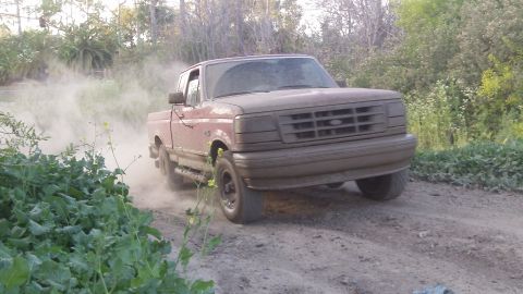 1995 Ford F-150 - This 1995 Ford F-150 is kicking up dust while driving on a dirt road.