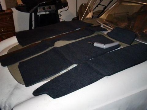 1969 Volvo P1800 - Carpet pieces are laid out on the hood of a car, with a drill resting on one of them.