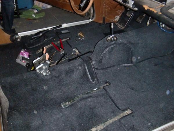 Interior of a car with carpet removed and parts on the floor