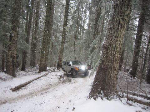 2008 Jeep Wrangler - A silver Jeep Cherokee XJ navigates a snow-covered path through a dense, frosted forest.