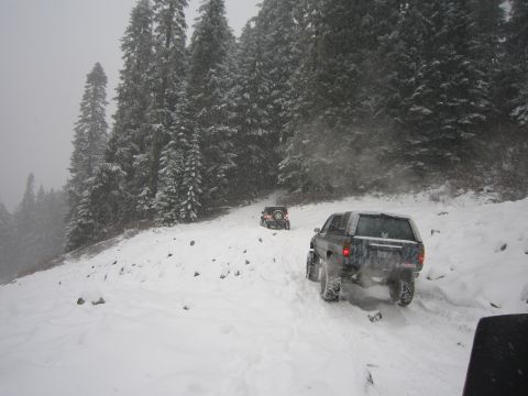2008 Jeep Wrangler - Two SUVs navigate a snow-covered mountain road during a snowfall.