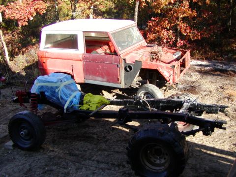 1976 Ford Bronco - A 1976 Ford Bronco body sits next to its disassembled chassis and engine, suggesting a restoration project in progress.