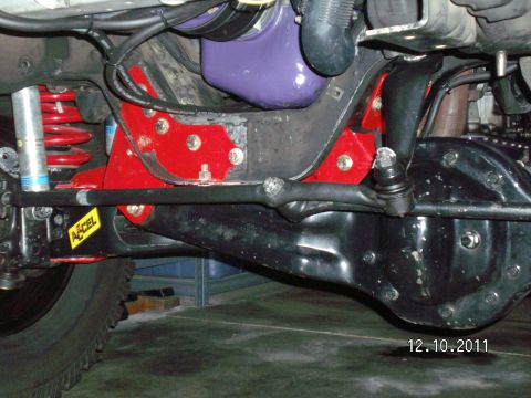 1996 Ford Bronco - Undercarriage view shows aftermarket suspension modifications with red brackets and a tie rod flip kit.