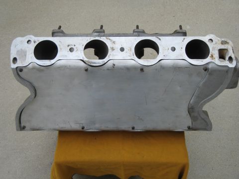 1969 Ford Mustang - Close-up of an aluminum intake manifold, likely for a V8 engine, resting on a yellow surface.