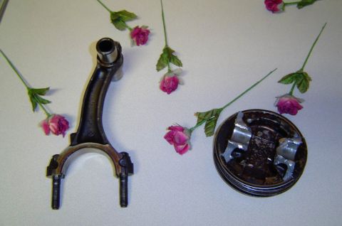 1993 Ford Bronco - Engine components, a connecting rod and a piston, are arranged with artificial pink flowers.