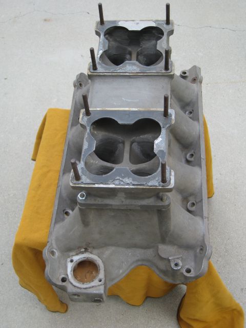 1969 Ford Mustang - An aluminum dual quad intake manifold rests on a yellow cloth against a concrete background.