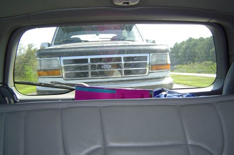 1993 Ford Bronco - The grille of a 1992 Ford F-Series truck is visible through the rear window of another vehicle.