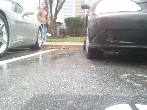 1999 Honda Civic - Two cars parked side-by-side on a wet asphalt lot with a woman standing between them.