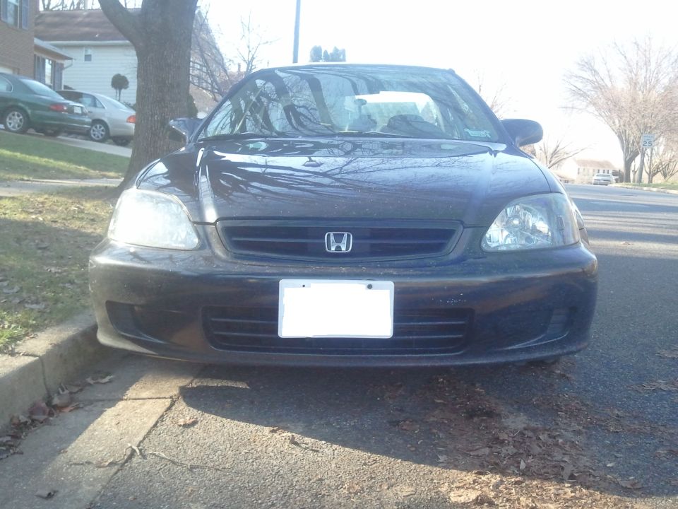 Front view of a dark Honda Civic parked at a curb on a residential street with bare trees