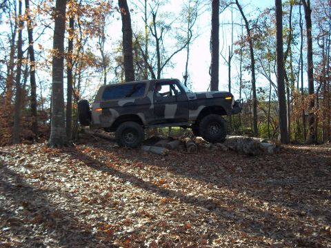 1979 Ford Bronco - Ford Bronco navigating an obstacle course in a forest during autumn.