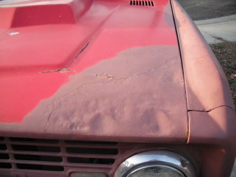 1968 Ford Bronco - The hood of a red 1968 Ford Bronco shows extensive rust damage and peeling paint, indicating areas of concern for body condition.