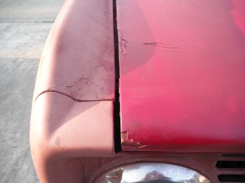 1968 Ford Bronco - Close-up of a car's body panel seam showing significant paint damage and rust.