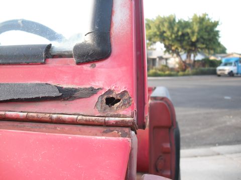 1968 Ford Bronco - Rust damage is visible on the body panel of a red vehicle.