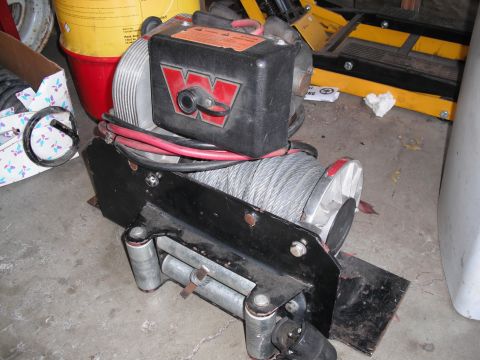 1968 Ford Bronco - A Warn winch with a prominent red 'W' logo and steel cable is shown, likely a vehicle accessory.