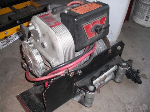 1968 Ford Bronco - Warn electric winch with red and black casing and steel cable.