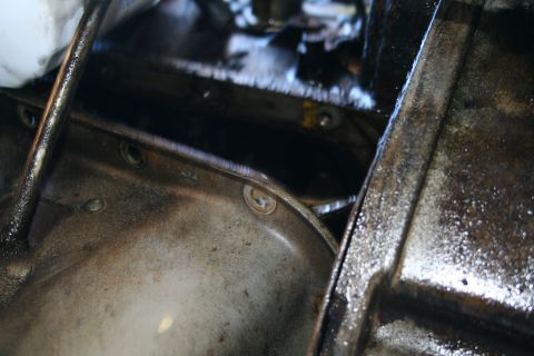 1982 Ford Bronco - Greasy transmission pan and oil pan assembly visible during transmission removal.