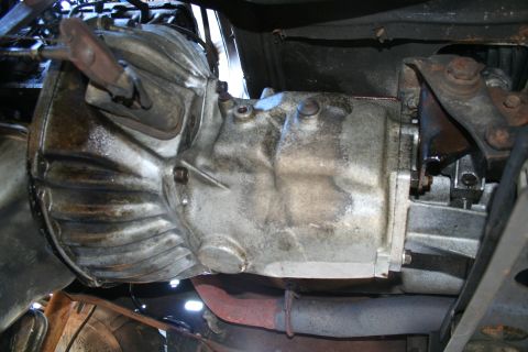1982 Ford Bronco - Underside view of a vehicle's transmission, showing its metallic components and signs of wear.
