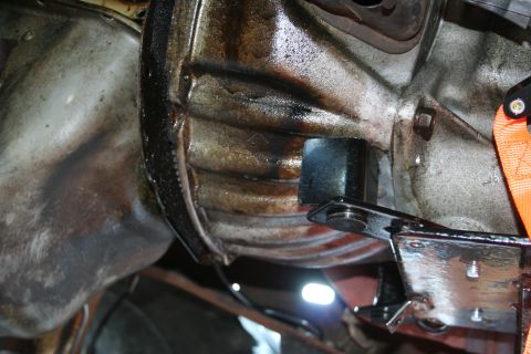 1982 Ford Bronco - Close-up view of a greasy transmission housing, with an orange strap visible.
