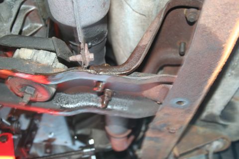 1982 Ford Bronco - Close-up of the undercarriage reveals rusted components and signs of fluid leakage.
