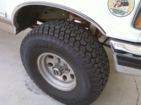 1996 Ford Bronco - Close-up of a white 1996 Ford Bronco's front tire and fender, a 'Northern Nevada's Four Wheeling Bronco Club' sticker.