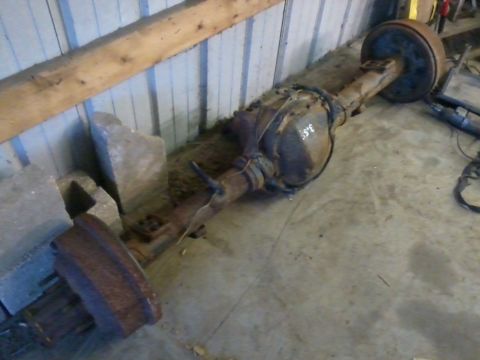 1995 Ford Bronco - A rusty rear axle assembly with drum brakes is stored indoors.
