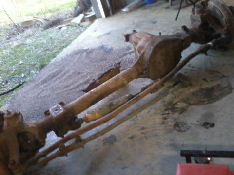 1995 Ford Bronco - A rusty front axle assembly, likely from an older truck or SUV, is shown on a concrete floor.