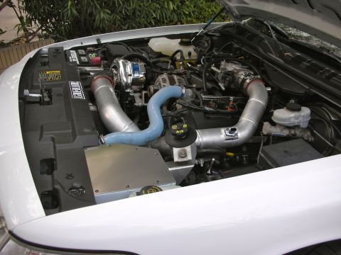2004 Ford Crown Victoria - Engine bay of a white vehicle modified with a supercharger system and custom intake.