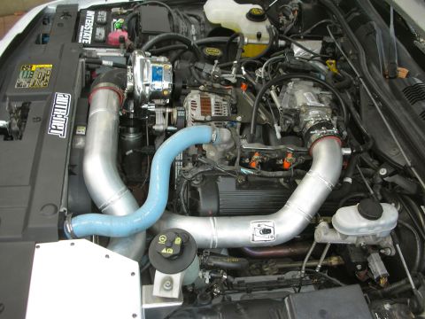 2004 Ford Crown Victoria - Engine bay with a supercharger system installed, custom intake piping and blue hoses.