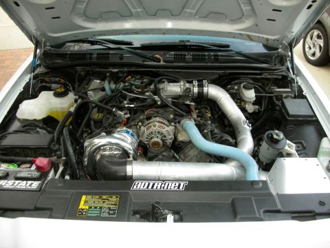 2004 Ford Crown Victoria - The engine bay of a 2004 Ford Crown Victoria features a prominent supercharger and custom intake piping, with ADTR.NET branding visible.