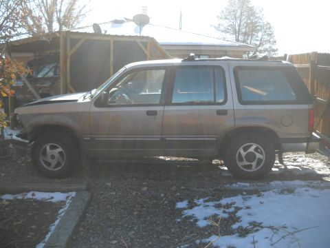 1992 Ford Explorer - Side profile of a 1992 Ford Explorer SUV parked in a gravel lot with some snow.