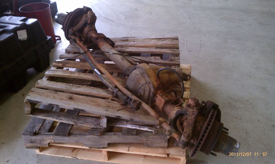 rusty front axle assembly on wooden pallets
