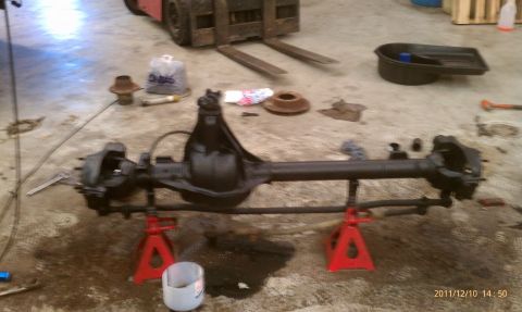1987 Ford Bronco - A front axle assembly is disassembled and laid out on jack stands in a workshop environment.