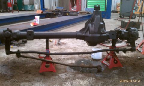 1987 Ford Bronco - A vehicle's front axle assembly is supported by jack stands in a workshop setting.