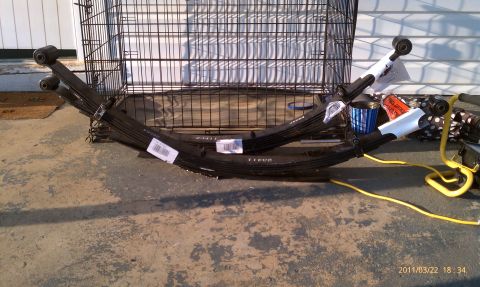 1987 Ford Bronco - Leaf springs are shown with labels and a yellow cable, placed on a concrete surface with a dog crate behind them.