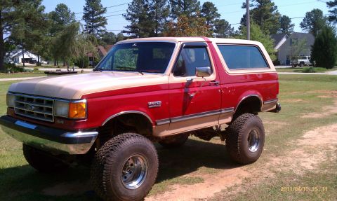 1987 Ford Bronco - This lifted 1987 Ford Bronco features a two-tone red and tan paint scheme and large off-road tires.