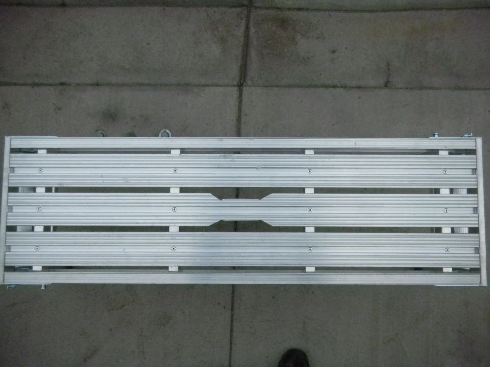 Overhead view of a silver aluminum slatted truck bed rack on concrete