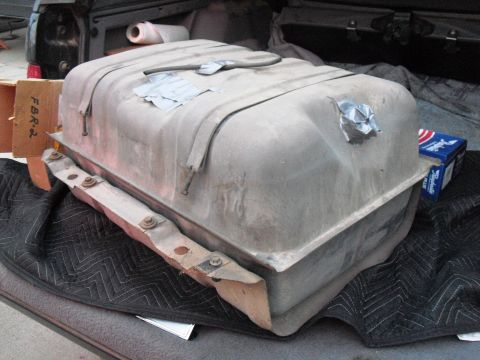 1986 Ford Bronco - Fuel tank with visible straps and duct tape repairs, resting on a quilted mat.