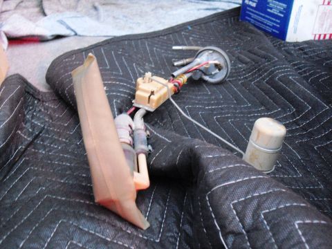 1986 Ford Bronco - A disassembled fuel pump assembly lies on a dark quilted mat, showing its various components and wiring.