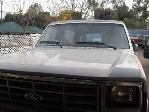 1986 Ford Bronco - The front view of a gray Ford Bronco shows its hood and grille, with a 'Ford' emblem visible.